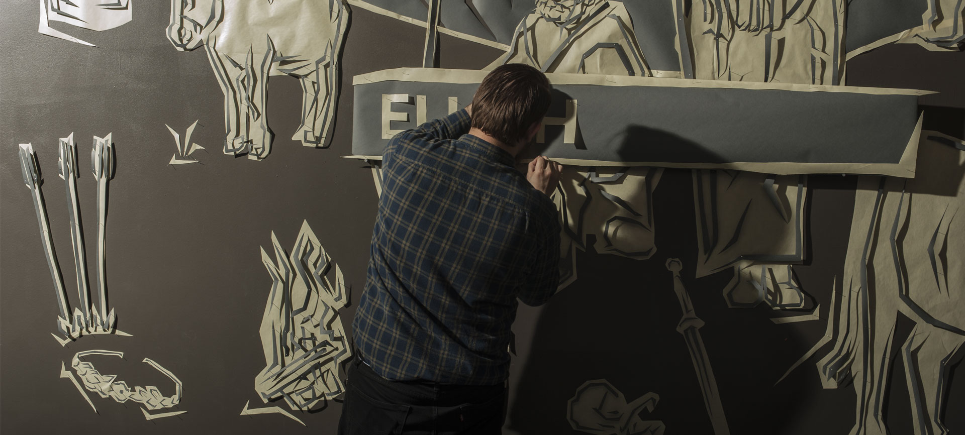 Photo of Will Truran installing a large cut paper mural